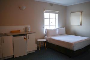 LindisfarneBeltana Hotel的一间小房间,配有床和小厨房