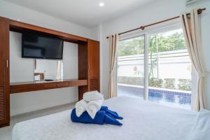 拉威海滩Jasmine Pool Villa in Nai Harn的一间卧室配有电视和一张带毛巾的床。