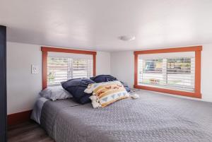 Apple ValleyNew calm & relaxing Tiny House w deck near ZION的一间卧室配有带枕头的床和2个窗户。