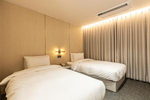 西归浦市Hotel The Grang Seogwipo的酒店客房设有两张床和窗户。