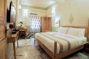斋浦尔Dev Mahal - A Boutique Heritage Hotel的酒店客房设有一张大床和一张书桌。