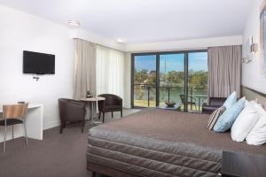 华纳海湾Macquarie 4 Star的酒店客房设有一张床、一张书桌和一个阳台。
