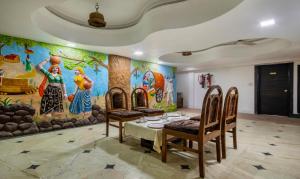 艾哈迈达巴德Treebo Trend Shree Krishna Palace的用餐室配有桌椅和壁画