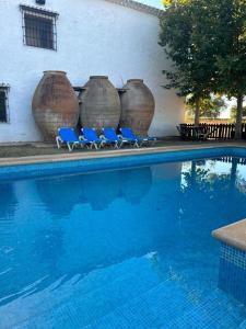 比利亚罗夫莱多La Huerta de Don Fernando的游泳池旁的三把蓝色椅子,带大花瓶