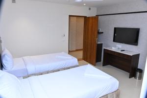 海得拉巴Grand Manor Suites的酒店客房设有两张床和电视。