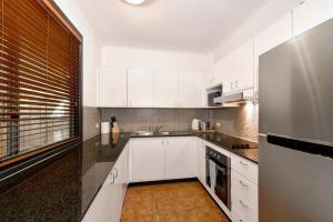 悉尼Beautiful apartment in Pyrmont的厨房配有白色橱柜和不锈钢冰箱