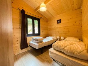 讷韦格利斯chalet nature sur la vallée de la Truyère的小木屋内的两张床,设有窗户