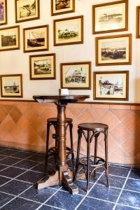 圣玛丽亚港ALEGRIA Bodega Real的墙上挂着照片的房间里一张桌子和两张凳子