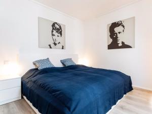 杜塞尔多夫Homefy Altstadt Apartment für 6 Personen, mit 2 Bädern und Balkon的卧室配有一张蓝色的床,墙上挂有两张照片