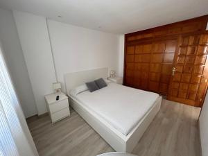 洛斯克里斯蒂亚诺斯Apartamento en Los Cristianos的卧室配有白色的床和木门