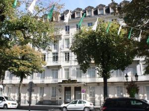 巴涅尔-德吕雄Appartement Bagnères-de-Luchon, 2 pièces, 4 personnes - FR-1-313-151的前面有旗帜的大型白色建筑