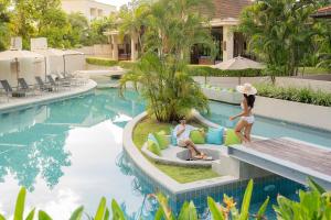 奈扬海滩Dewa Phuket Resort & Villas的两个女人坐在度假村游泳池边的椅子上