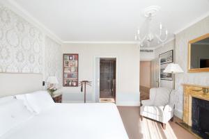 巴塞罗那Hotel El Palace Barcelona的一间白色卧室,配有一张床和一个壁炉