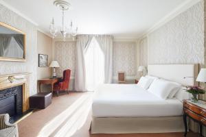 巴塞罗那Hotel El Palace Barcelona的卧室配有一张白色大床和壁炉