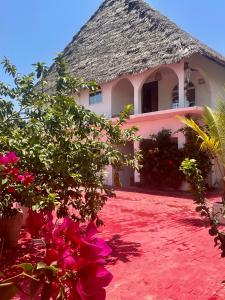 帕杰Villa Euphoria - Adults Only的茅草屋顶和粉红色花卉的房子