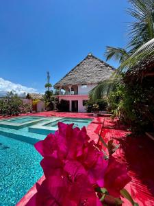 帕杰Villa Euphoria - Adults Only的一座房子旁的游泳池,里面种着粉红色的花