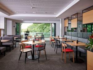 汉密尔顿汉密尔顿泰努伊宜必思酒店的餐厅设有木桌、椅子和大窗户。