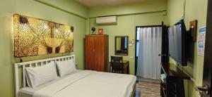 清迈禾住宿加早餐旅馆的卧室配有白色的床和电视。