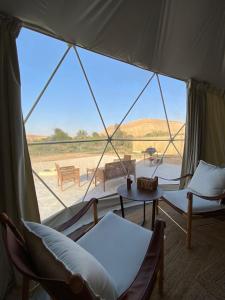 Al Fawwāzمنتجع جلامبنغ - Glamping Resort的一个带椅子和桌子的帐篷和一个大窗户