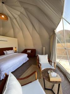 Al Fawwāzمنتجع جلامبنغ - Glamping Resort的帐篷卧室配有两张床和一张桌子