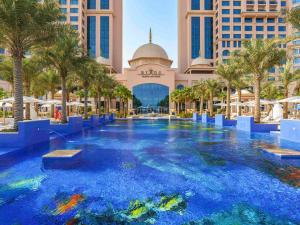 阿布扎比Rixos Marina Abu Dhabi的棕榈树度假村中间的游泳池