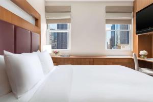 纽约Hotel 57 by LuxUrban的卧室设有一张白色大床和两个窗户。