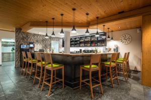 Schiers阿尔皮纳酒店的餐厅内的酒吧设有木制天花板和木凳