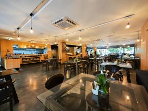 曼谷Galleria 12 Sukhumvit Bangkok by Compass Hospitality的一间带桌椅的餐厅和一间厨房