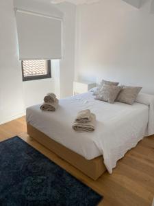 格拉塔略普斯Fam de Vida的白色卧室,配有带毛巾的床
