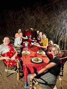 MakuyuniMaasai Eco Boma & Lodge - Experience Maasai Culture的一群坐在桌子旁吃食物的人