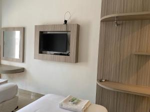 SukaramiBelvena Makati Hotel的一间墙上配有电视的房间和一张床