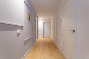 马德里Uma Suites O'Donnell的走廊设有白色墙壁和木地板