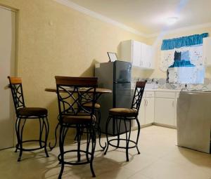 圣詹姆斯Kenridge Residences的厨房配有四把椅子、一张桌子和一台冰箱