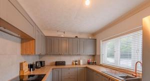 RamseyExtensive 4 bed close to Peterborough的厨房配有木制橱柜、水槽和窗户。