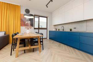 华沙Cozy & Spacious Family Apartment by Renters的厨房配有木桌和蓝色橱柜。