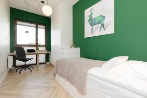 华沙Cozy & Spacious Family Apartment by Renters的一间卧室设有绿色的墙壁、一张床和一张书桌