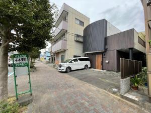 沼津Guest House Numazu Port - Vacation STAY 18050v的停在大楼旁边的停车场的白色汽车