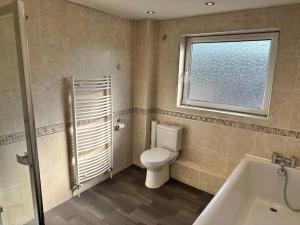 武姆韦尔Spacious 3 bed house in Wombwell的一间带卫生间、窗户和浴缸的浴室