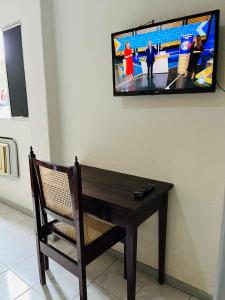 累西腓Hotel América的墙上的电视机,配有木桌和椅子