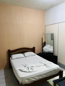 累西腓Hotel América的一间卧室配有一张带白色床单和镜子的床