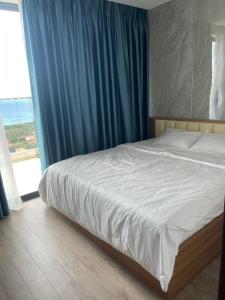 绥和市Toàn Tâm Apec的一间卧室配有一张带蓝色窗帘的床和窗户