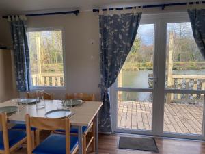 VoyennesMobil-home confort face à l'étang的一间带桌子和大窗户的用餐室
