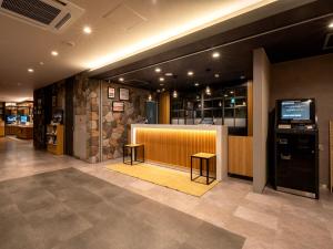 富士河口湖Super Hotel Fujikawaguchiko Tennenonsen的大堂设有带2张凳子的柜台和酒吧