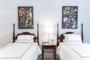 普利茅斯Biddle Point Inn的卧室内的两张床,墙上挂有绘画作品