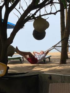 卡卢特勒Hotel Coconut Bay的躺在树下吊床上的男人