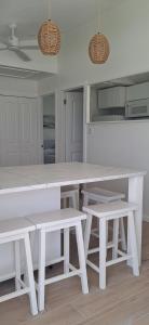 Head of BayConch Club Cottage的白色的厨房配有白色的桌子和长凳