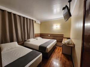 里贝朗普雷托Aurora Hotel的酒店客房设有两张床和电视。