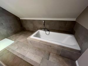 Bolderberg波儿德尔豪斯公寓的浴室铺有瓷砖地板,配有白色浴缸。