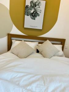梳邦再也Harmony and Deluxe Studio Subang Jaya的一张带枕头的白色床和墙上的照片