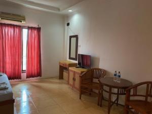 SukaramiBelvena Makati Hotel的客厅配有电视和桌椅